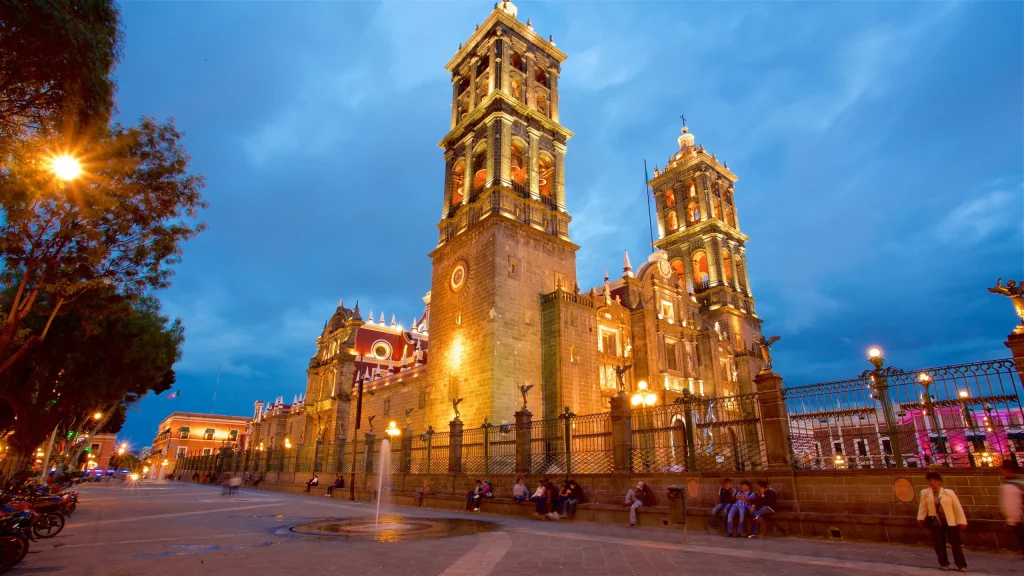 Catedral de Puebla iluminada durante el atardecer con turistas caminando en la plaza, Qué hacer en Puebla