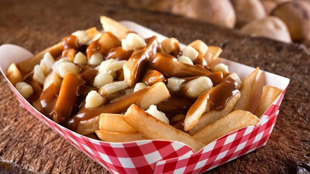 Poutine tradicional servido en un plato hondo con salsa caliente y queso fundido
